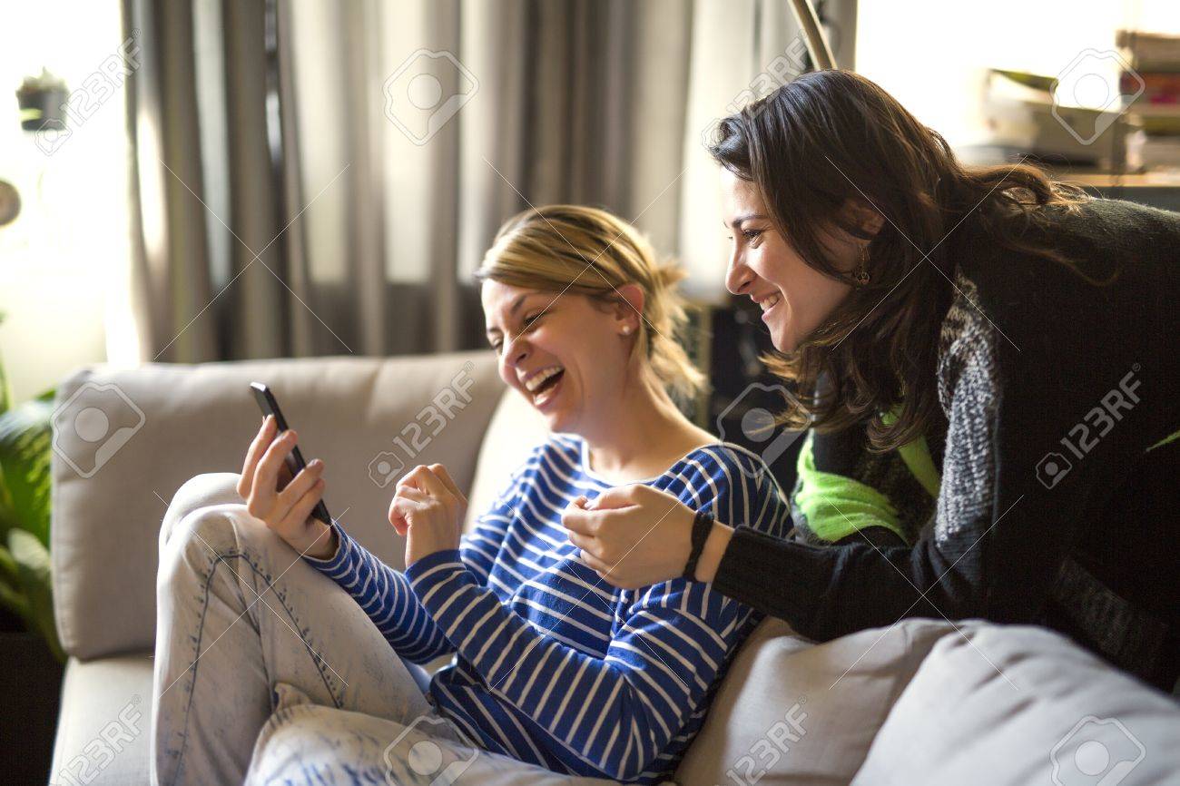 人との関わり 2 人の女の子は話すこととソファの上に携帯電話を使用して の写真素材 画像素材 Image