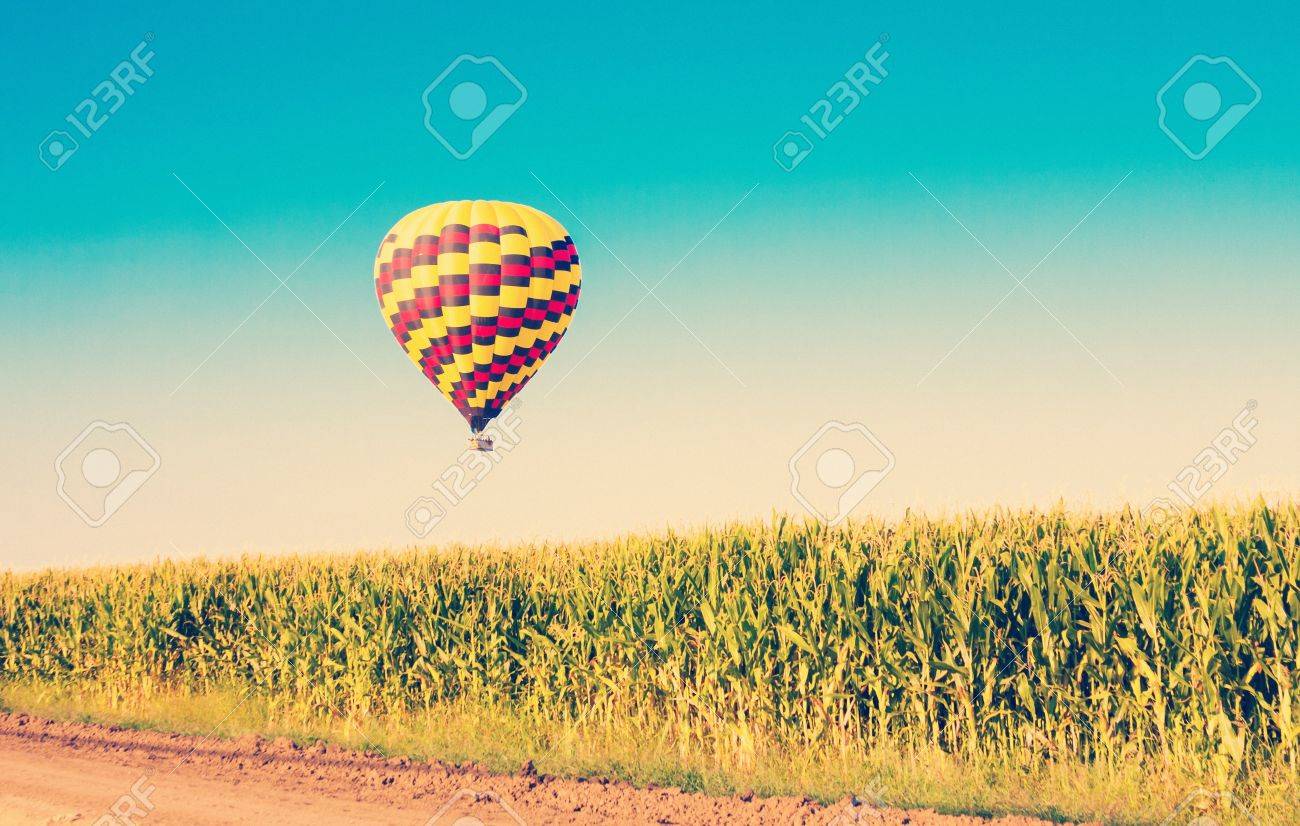 Hot air balloon flying over corn fields against blue sky in old style - 21167027 Hot air balloon flying over corn fields against blue sky in old style - 21167027