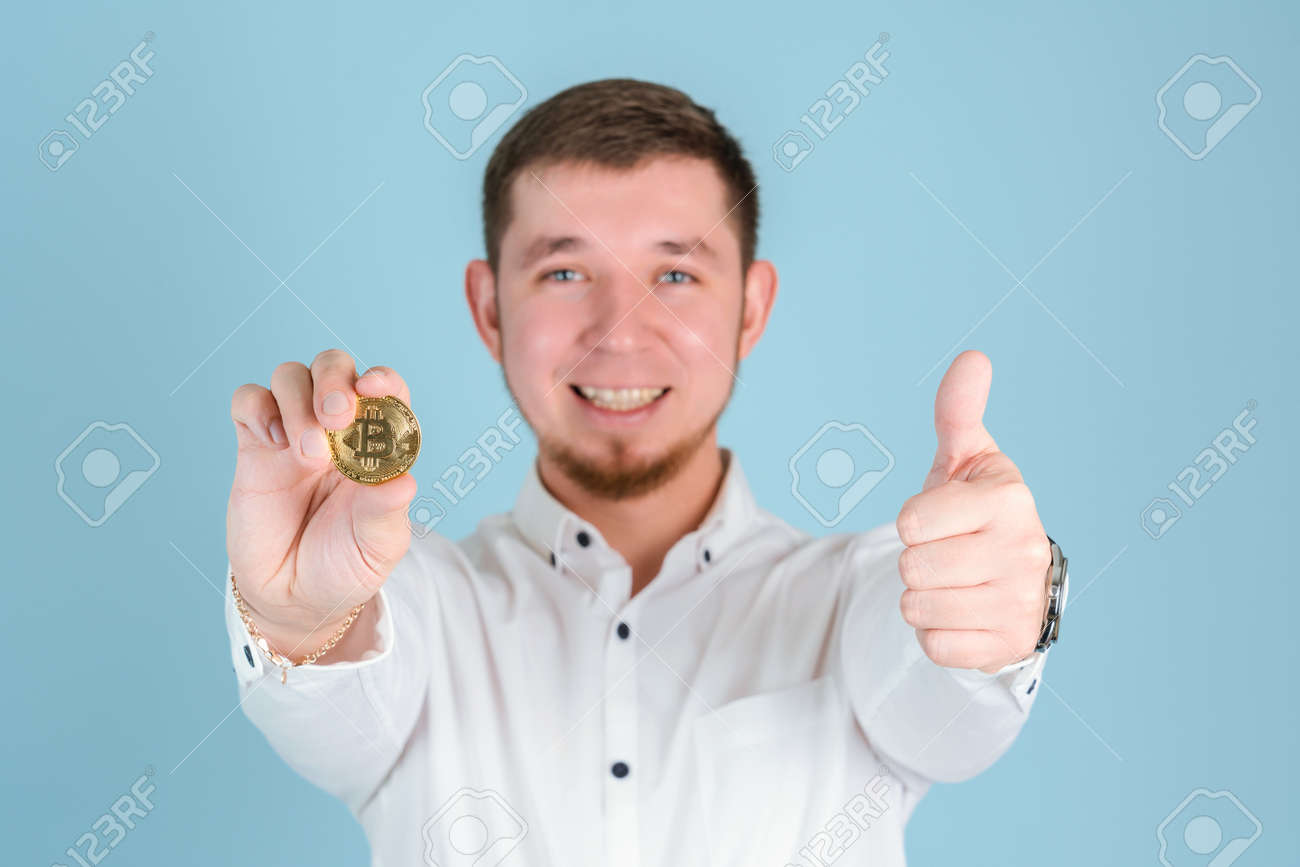 笑顔のビジネスマンは、腕の長さでビットコインゴールドコインを保持し、親指を立てるジェスチャーの選択的なフォーカスを示していますの写真素材・画像素材  Image 180187961