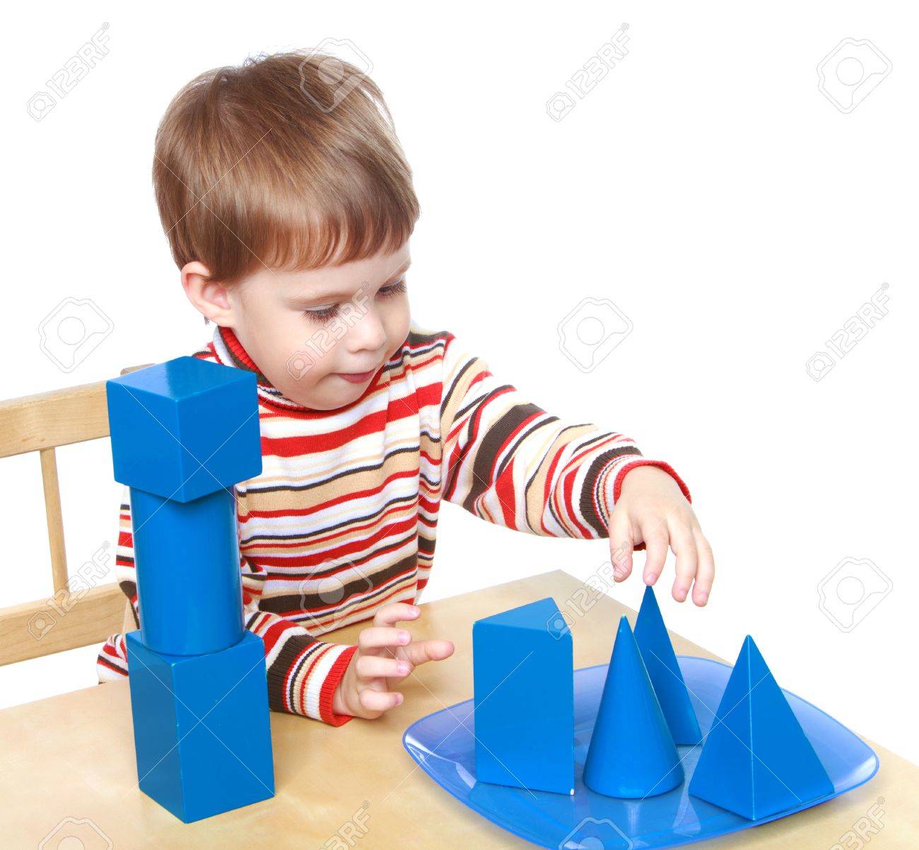 Little boy plays cubes and cones sitting at the table, Montessori kindergarten.Isolated on white background, Lotus Childrens Center. - 36176019 Little boy plays cubes and cones sitting at the table, Montessori kindergarten.Isolated on white background, Lotus Childrens Center. - 36176019