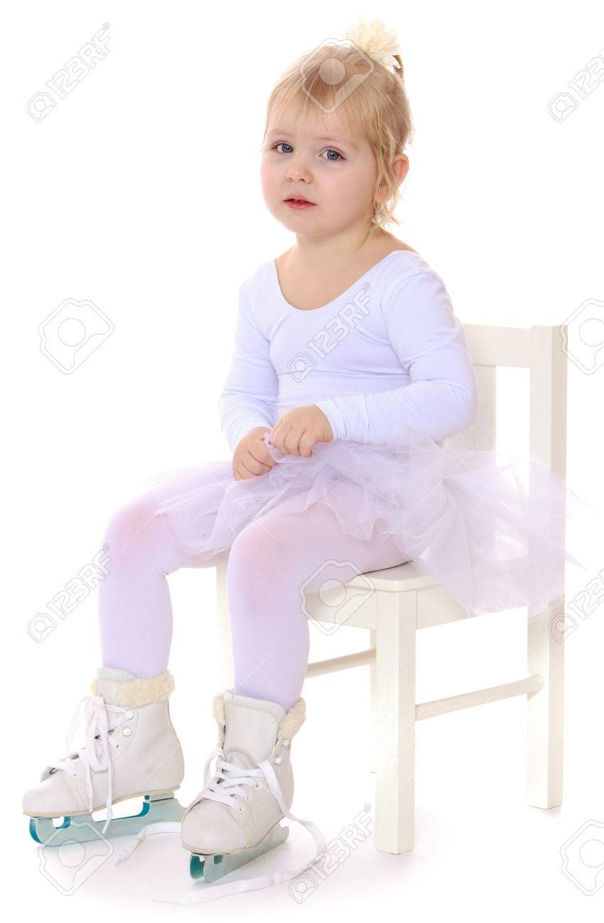 かわいい女の子 将来フィギュア スケート ホワイト スポーツ ドレスを着て椅子に座るし 白い背景のスキッド分離された 2 つのフィギュア スケート の写真素材 画像素材 Image
