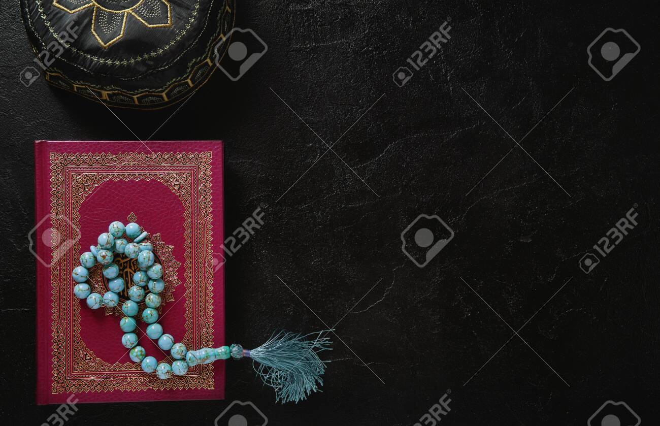 Koran with rosary beads and muslim hat on black slate texture background. Islamic concept with copy space - 129152633 Koran with rosary beads and muslim hat on black slate texture background. Islamic concept with copy space - 129152633