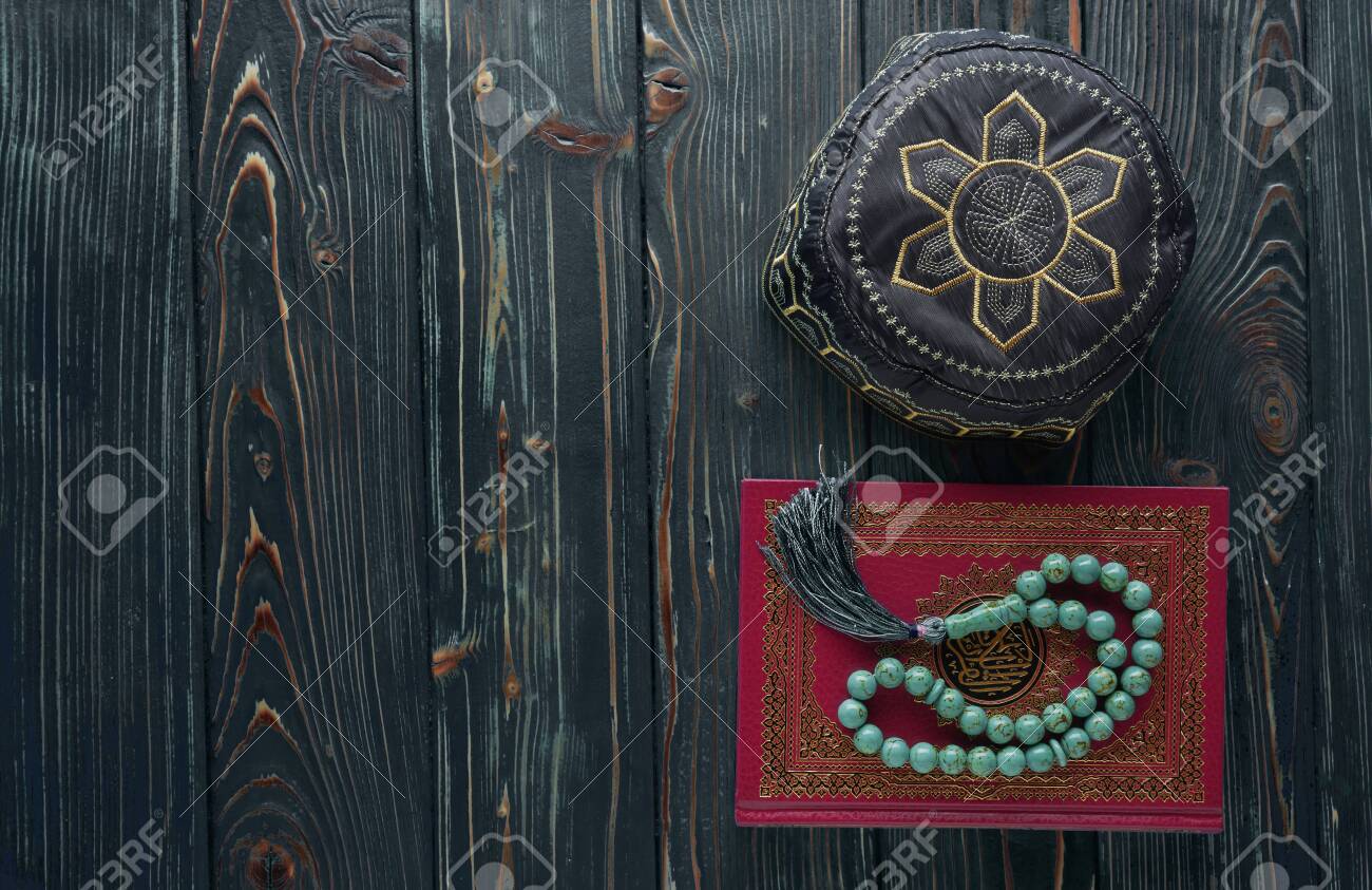 Islamic book Quran with rosary beads and muslim hat on wooden background. Islamic concept with copy space - 129083795 Islamic book Quran with rosary beads and muslim hat on wooden background. Islamic concept with copy space - 129083795