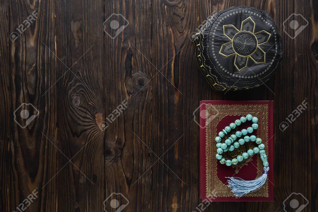 Koran with rosary beads and pray hat on wooden background. Islamic concept with copy space - 129083801 Koran with rosary beads and pray hat on wooden background. Islamic concept with copy space - 129083801