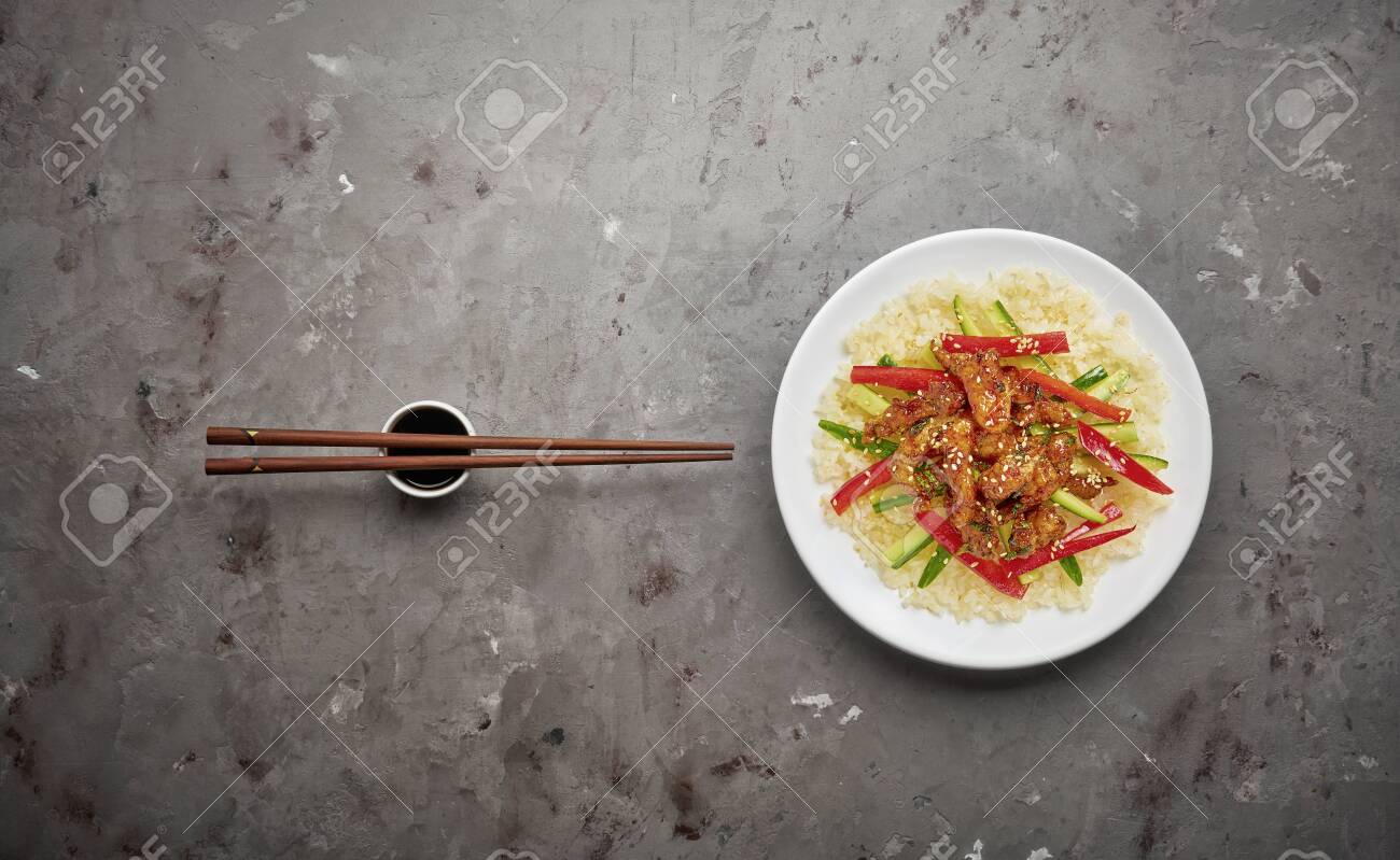 Stir-fry chicken meat, vegetables and rice on grey stone background. Copy space, top view - 129152648 Stir-fry chicken meat, vegetables and rice on grey stone background. Copy space, top view - 129152648