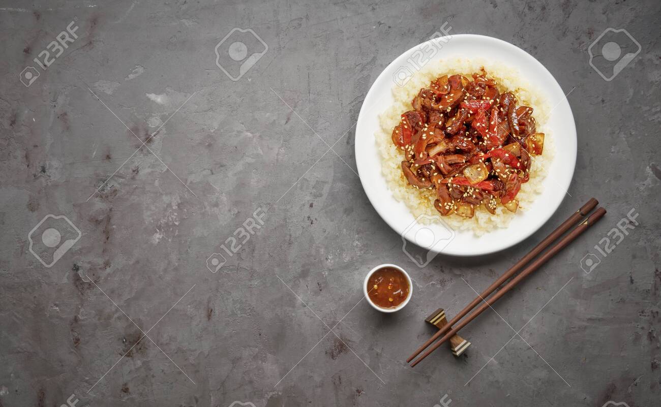 Sweet and Sour fried pork chunks with vegetables and rice on grey stone background. Top view with copy space - 129147166 Sweet and Sour fried pork chunks with vegetables and rice on grey stone background. Top view with copy space - 129147166