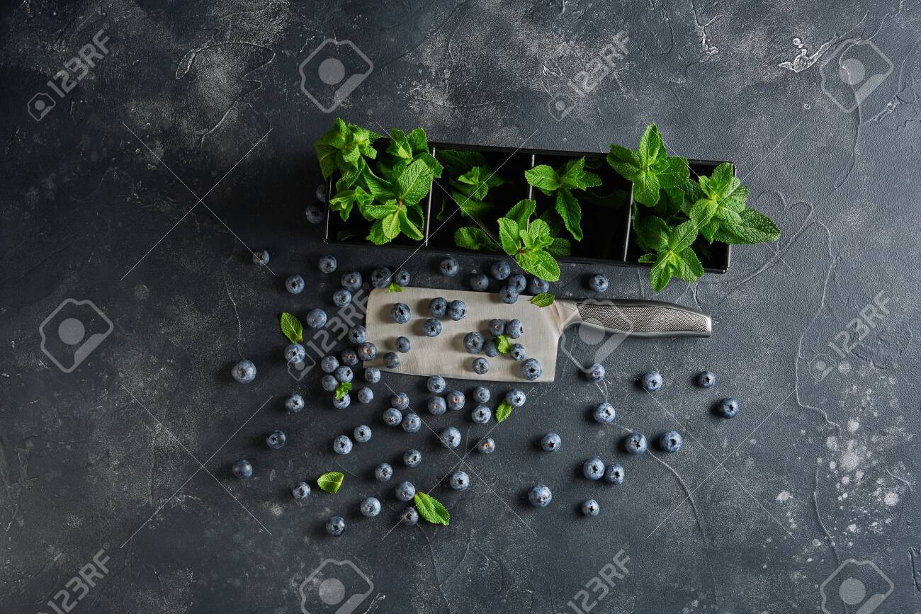 Top view of blueberries with fresh mint on dark rustic background with copy space. - 131904920 Top view of blueberries with fresh mint on dark rustic background with copy space. - 131904920
