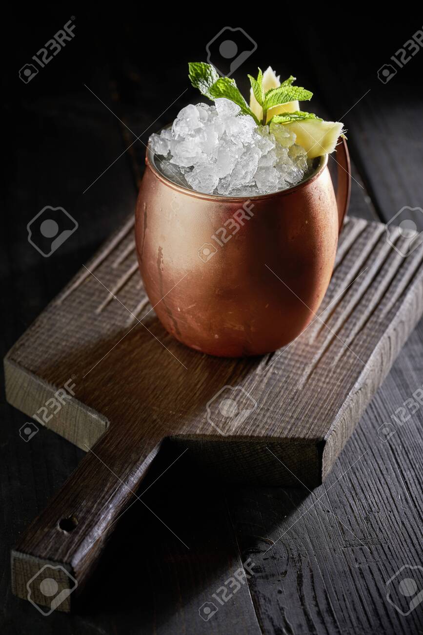 Cold Moscow Mule cocktail in copper mug on the rustic wooden background - 131305101 Cold Moscow Mule cocktail in copper mug on the rustic wooden background - 131305101