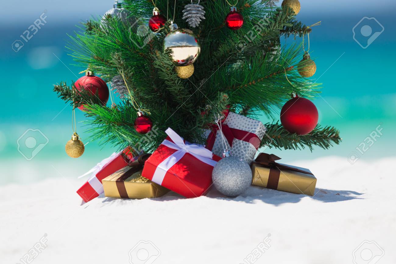 一部の国ではクリスマスが夏に過ごします 美しいクリスマスツリーは 夏の太陽の下で白い砂浜に座っています その下に包まれた贈り物があります コピーまたはメッセージの下のスペース の写真素材 画像素材 Image