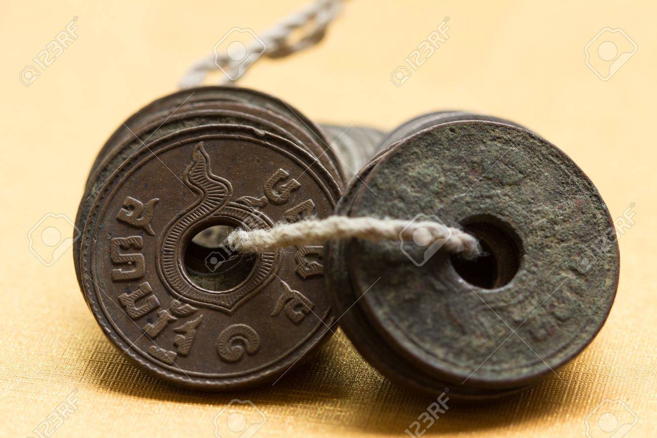 タイ古代硬貨は真ん中の穴で鋳造されました。収集する硬貨を運ぶ簡単な方法はそれらの穴を通して文字列です。の写真素材・画像素材 Image 42938124