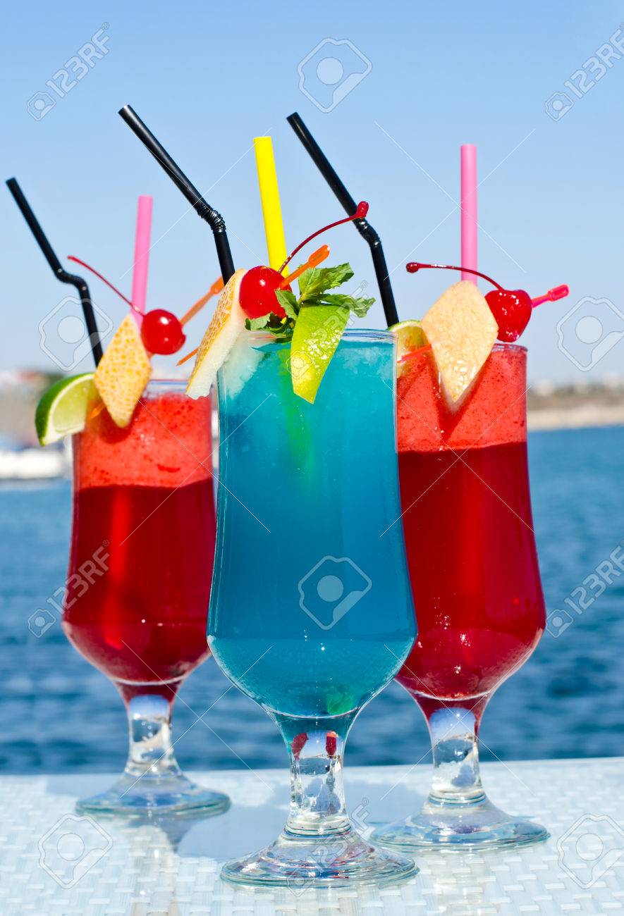 夏の赤と青いフルーツ カクテル カラフルなのエキゾチックなドリンクは バック グラウンドで海辺の岩の上 の写真素材 画像素材 Image