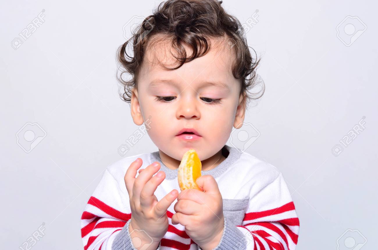 Portrait D Un Joli Bebe Mange Une Orange Un Enfant Age D Un An Mange Des Fruits Tout Seul Adorable Garcon Aux Cheveux Boucles Ayant Faim En Regardant Une Tranche D Orange Banque D Images Et Portrait D Un Joli Bebe Mange Une Orange Un Enfant Age D Un An Mange Des Fruits Tout Seul Adorable Garcon Aux Cheveux Boucles Ayant Faim En Regardant Une Tranche D Orange Banque D Images Et