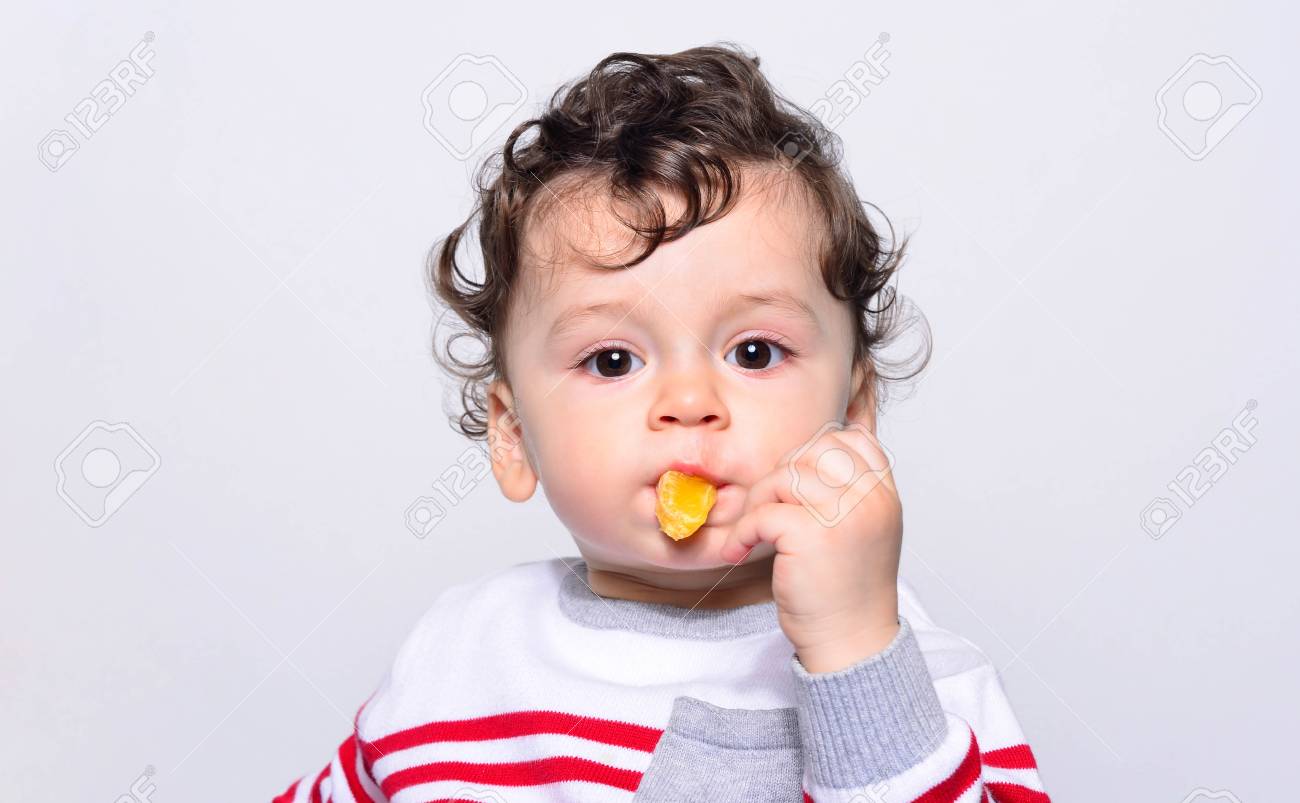 Portrait D Un Joli Bebe Mange Une Orange Un Enfant Age D Un An Mange Des Fruits Tout Seul Adorable Garcon Aux Cheveux Boucles Ayant Faim Mordant Sur Une Tranche D Orange Banque D Images Et