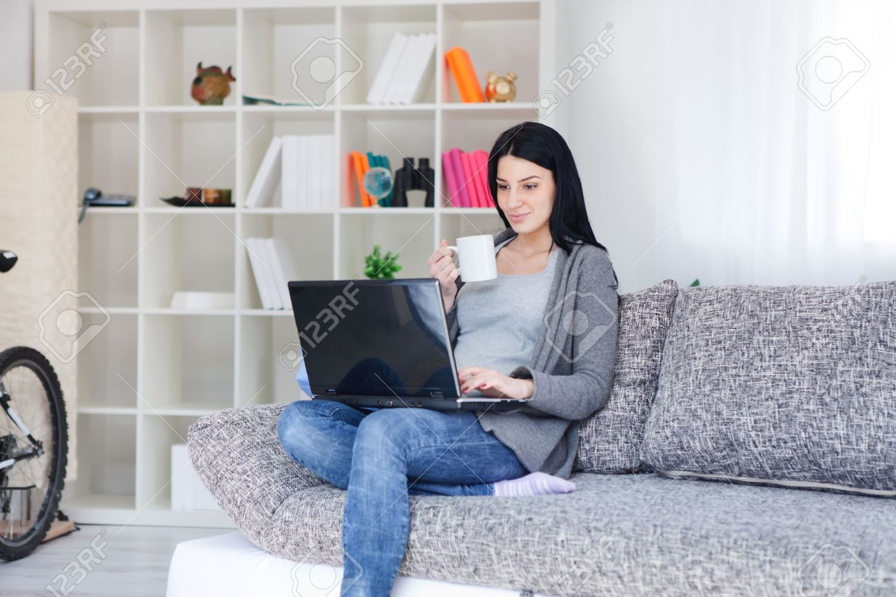 Woman Holding A Mug While Using A Laptop In Her Living Room Stock Photo, Picture And Royalty Free Image. Image 13523503.
