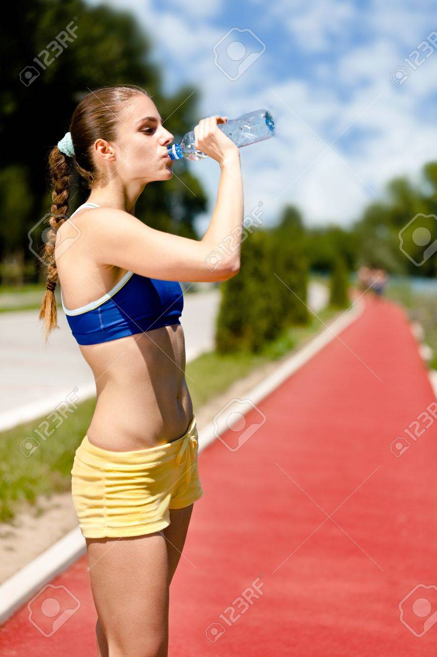 のどが渇いての若い女性の飲料水 トレーニング後の水和 の写真素材 画像素材 Image