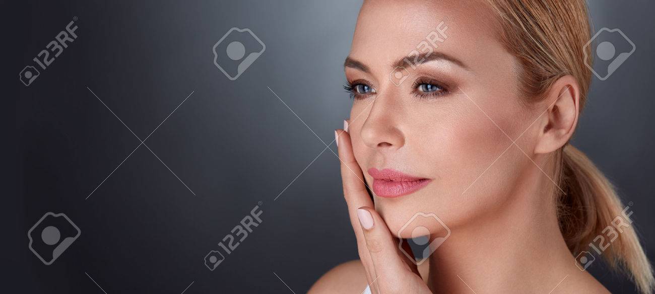 彼女の顔の皮膚と感じる柔らかさに触れて美しい中央高齢女性 の写真素材 画像素材 Image