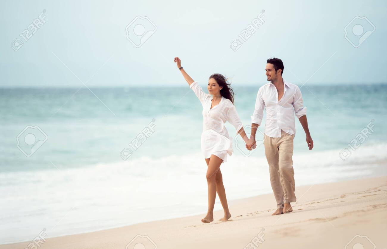 Couple Walking On Beach. Young Happy Couple Walking On Beach Smiling  Holding Hands Stock Photo, Picture and Royalty Free Image. Image 125195206.