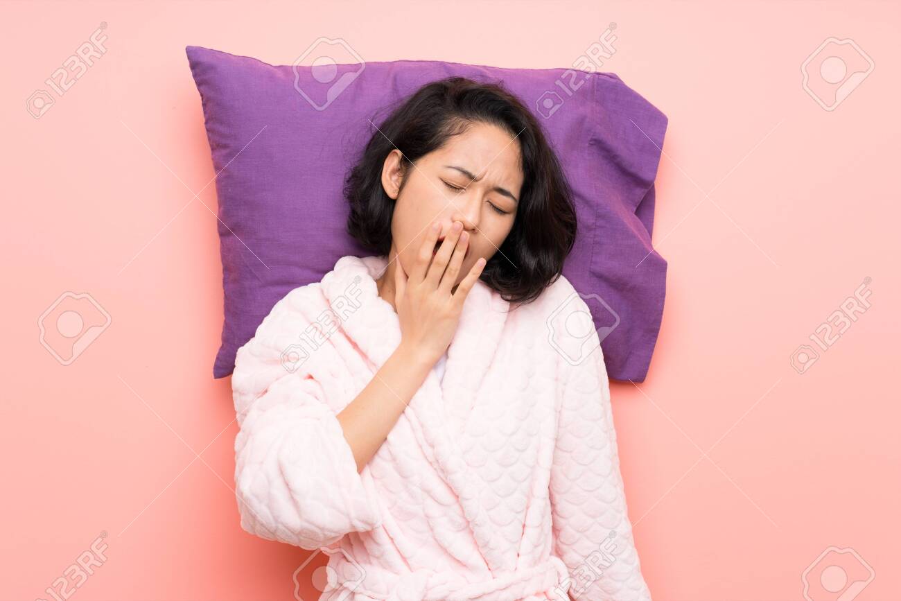 Asian young woman in pajamas yawning - 130613296 Asian young woman in pajamas yawning - 130613296