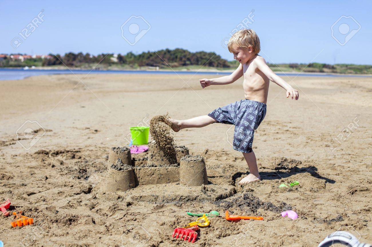 85143676-boy-kicking-against-sandcastle-on-beach.jpg
