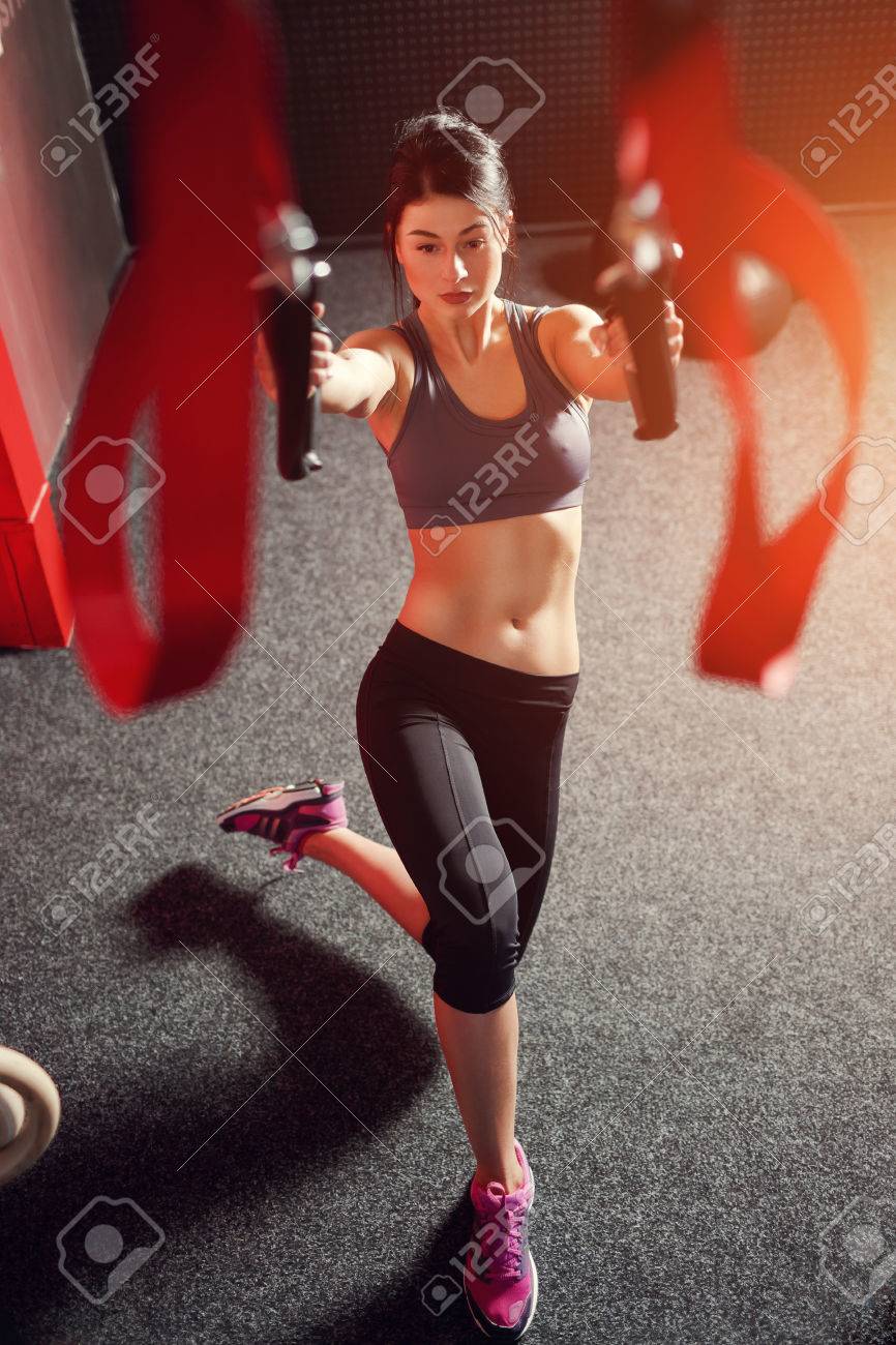 Crossfit training TRX straps. Young attractive brunette engaged cross fit on the suspension in the gym. - 38651356 Crossfit training TRX straps. Young attractive brunette engaged cross fit on the suspension in the gym. - 38651356