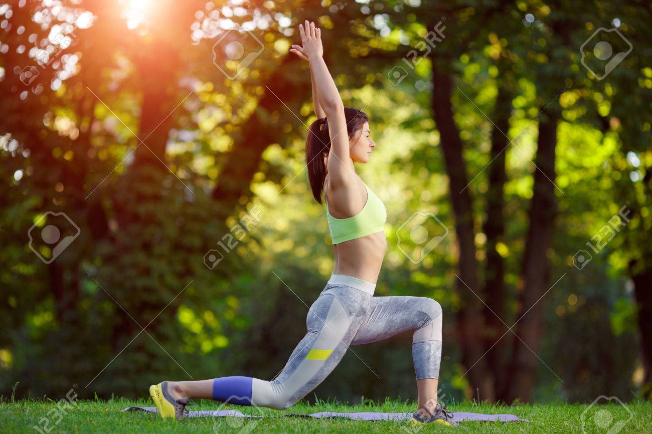Young smiling woman doing fitness exercises in the park on the green grass. Fitness training in the sunlight. - 43152812 Young smiling woman doing fitness exercises in the park on the green grass. Fitness training in the sunlight. - 43152812