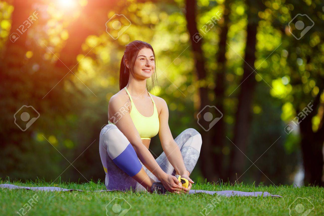Young smiling woman doing fitness exercises in the park on the green grass. Fitness training in the sunlight. - 43152820 Young smiling woman doing fitness exercises in the park on the green grass. Fitness training in the sunlight. - 43152820