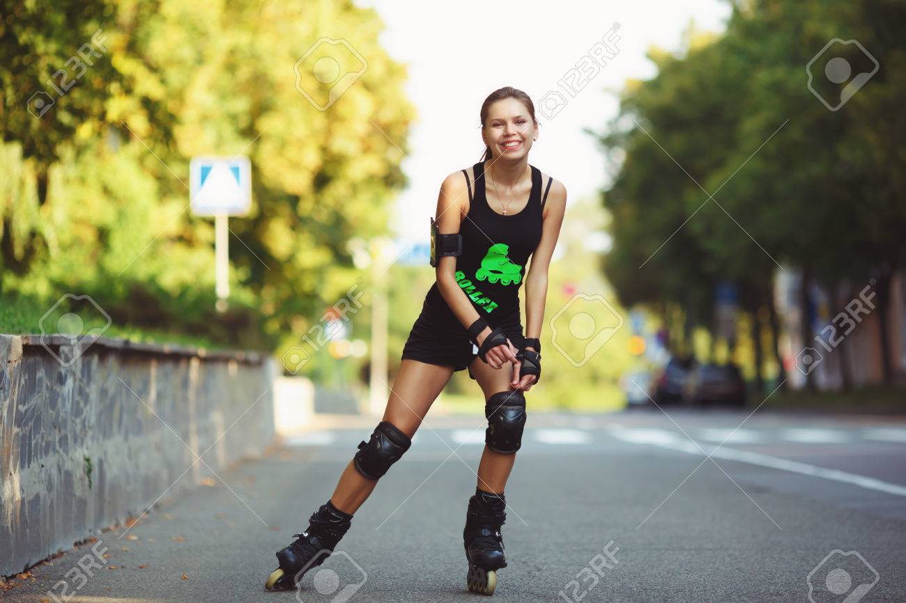 Atlética Hermosa Mujer, En Ropa Deportiva Negro, Al Patín De Ruedas El Camino. Chica Alegre Patines En Los Del Sol Poniente. Estilo De Vida Activo Fotos, Retratos, Imágenes