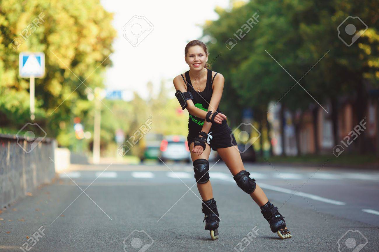 Atlética Hermosa Mujer, En Ropa Deportiva Negro, Al Patín De Ruedas El Camino. Chica Alegre Patines En Los Del Sol Poniente. Estilo De Vida Activo Fotos, Retratos, Imágenes