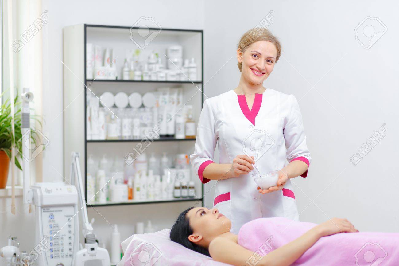 Young woman beautician is doing the cleaning procedure in the beauty salon. Face Skin Care. Cleansing Procedure. Cosmetology. - 54862587 Young woman beautician is doing the cleaning procedure in the beauty salon. Face Skin Care. Cleansing Procedure. Cosmetology. - 54862587