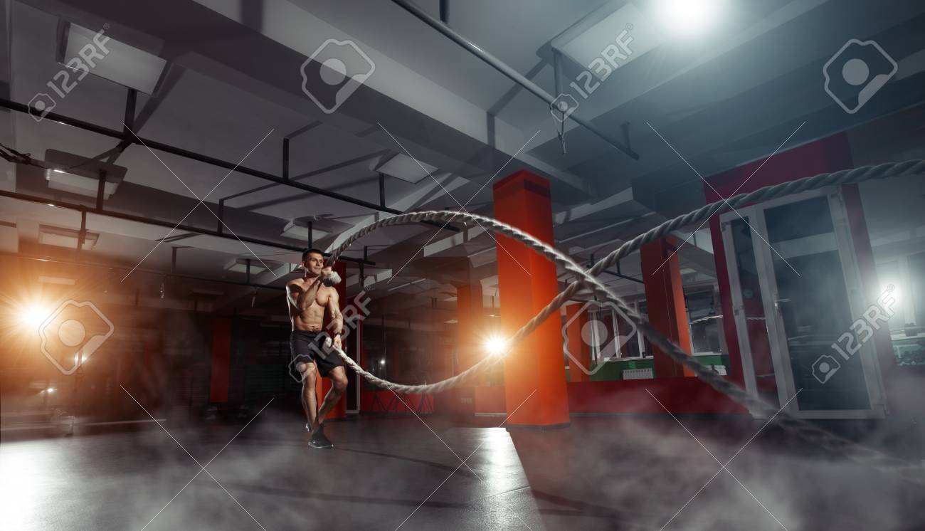 Fitness man working out with battle ropes at gym. Battle ropes fitness man at gym workout exercise fitted body. Fitness man training with battle rope in fitness club. Training with battle rope - 66304161 Fitness man working out with battle ropes at gym. Battle ropes fitness man at gym workout exercise fitted body. Fitness man training with battle rope in fitness club. Training with battle rope - 66304161