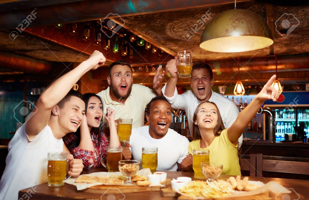 Happy friends having fun in pub watching sport in TV together. - 107927688 Happy friends having fun in pub watching sport in TV together. - 107927688