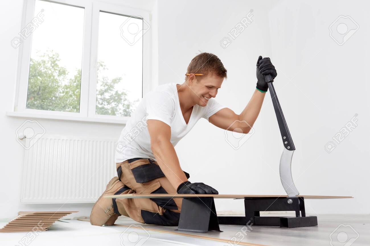 Worker cut wooden batten for laminate floor, floating wood tile - 143426213 Worker cut wooden batten for laminate floor, floating wood tile - 143426213