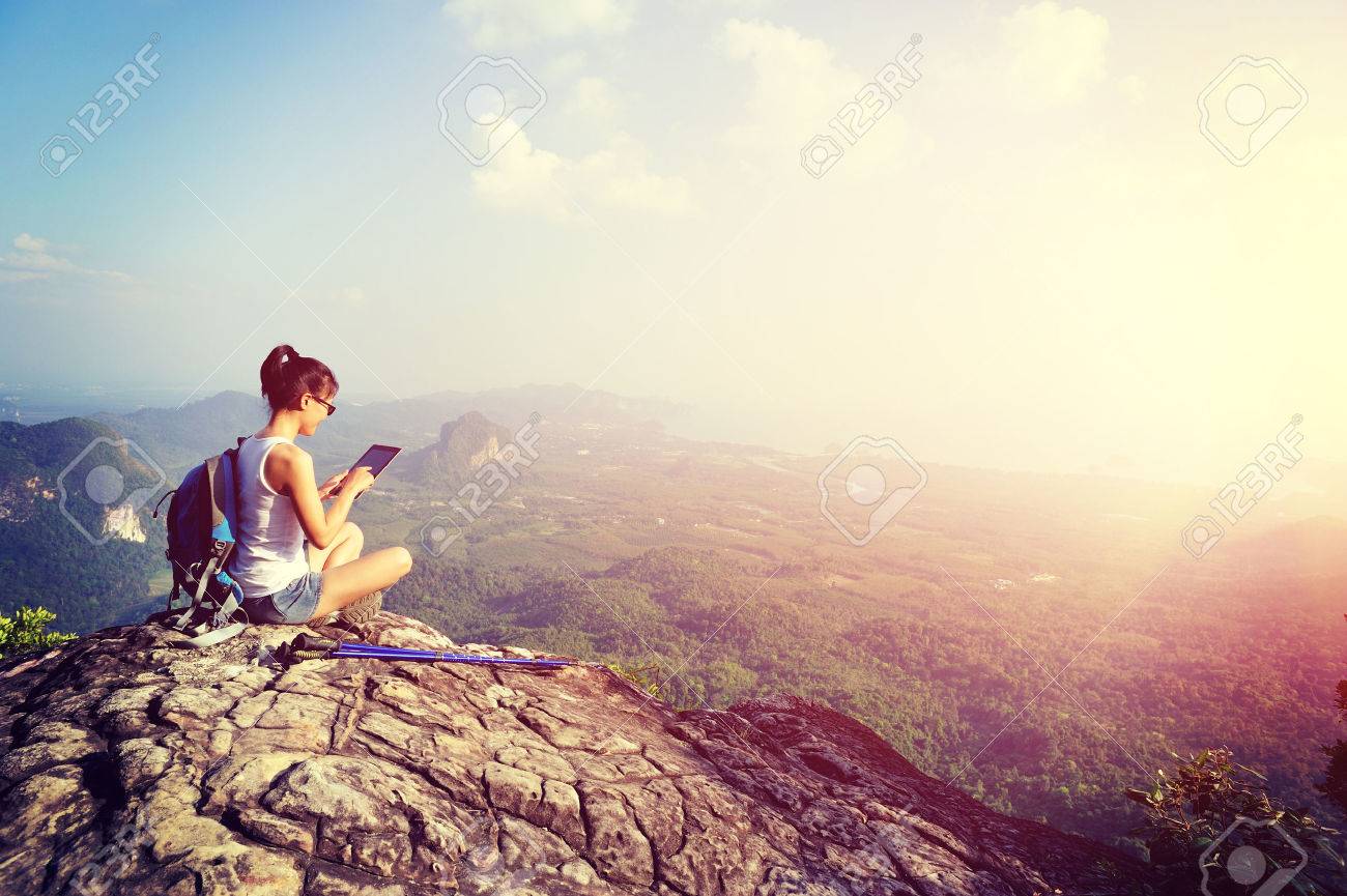 woman hiker use digital tablet at mountain peak - 50006725 woman hiker use digital tablet at mountain peak - 50006725