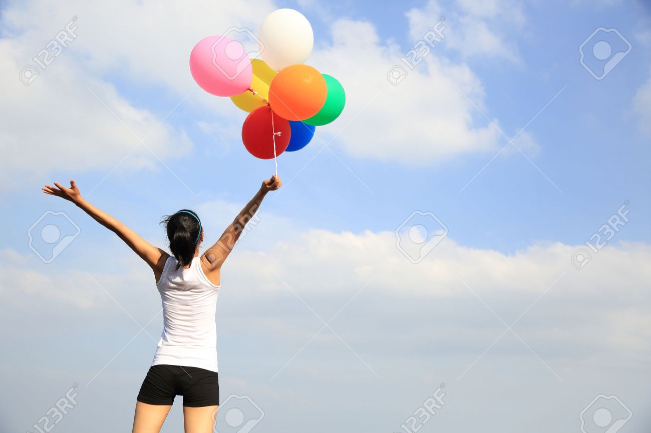 young woman cheering on mountain peak with colorful balloons - 51394096 young woman cheering on mountain peak with colorful balloons - 51394096