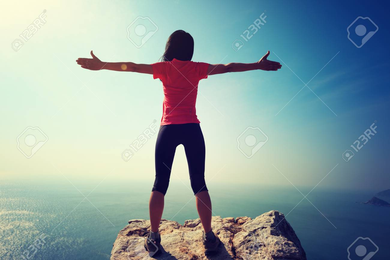 freedom female standing with outstretched arms on sunrise windy