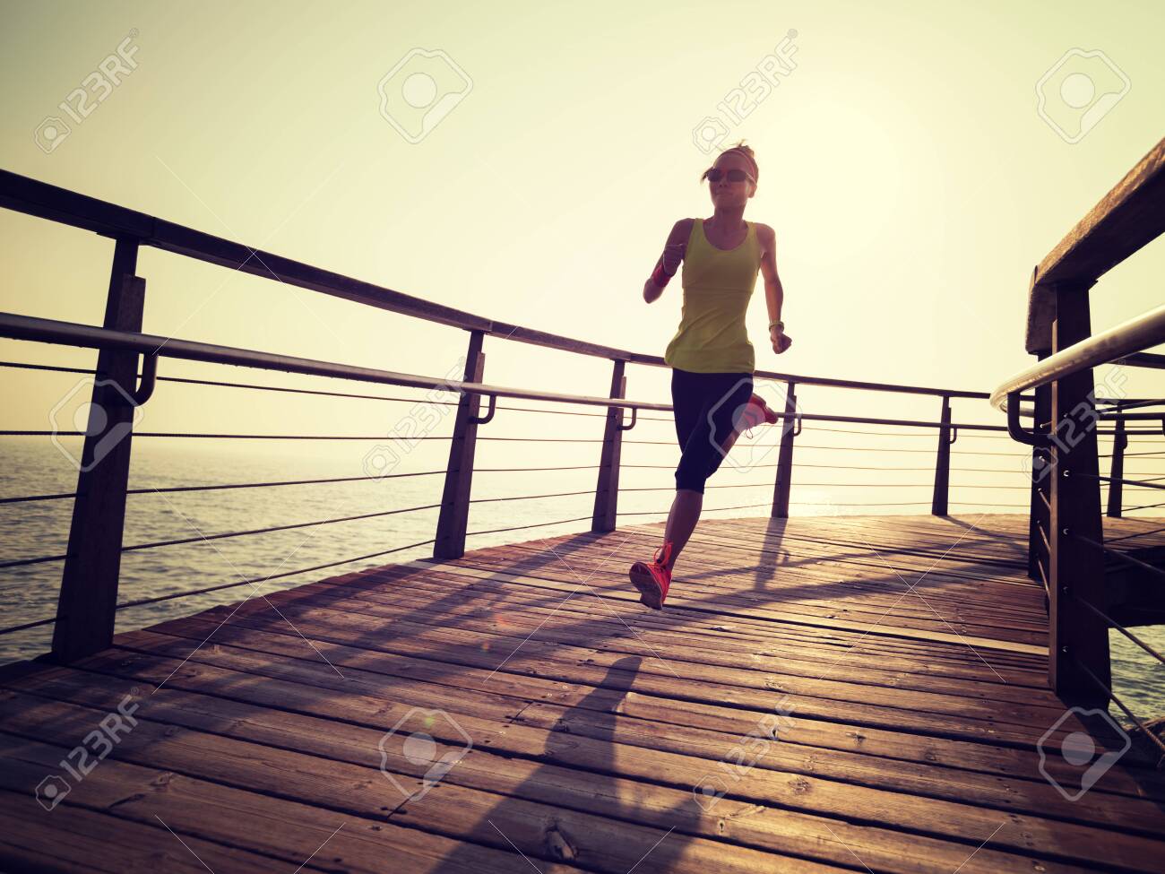 sporty fitness female runner running on seaside boardwalk during sunrise - 120462062 sporty fitness female runner running on seaside boardwalk during sunrise - 120462062
