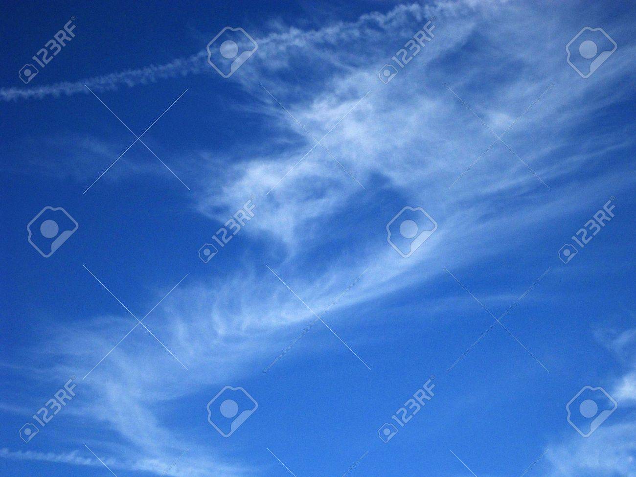 wispy jet vapor trails mingle with cirrus clouds in a deep blue vapor trails