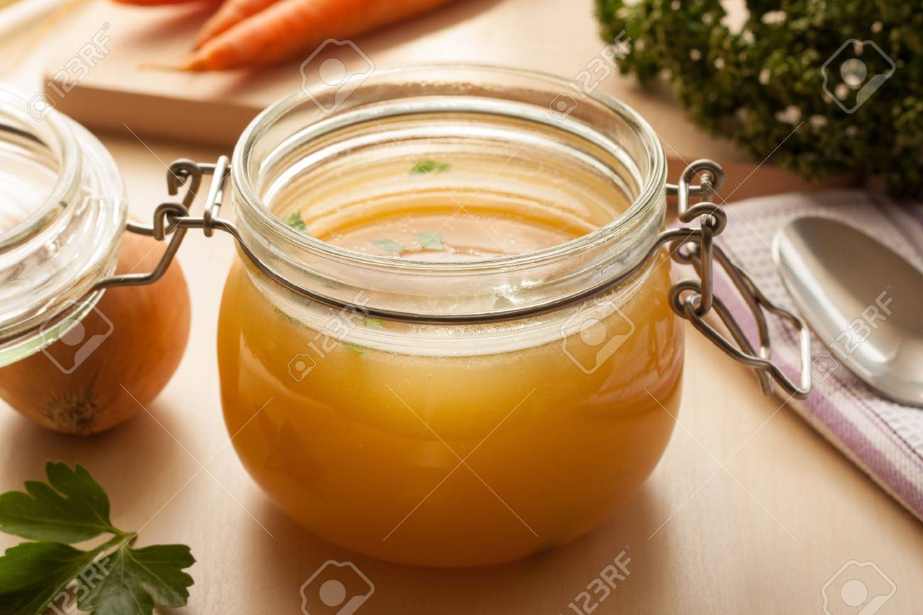 Bone broth made from chicken in a glass jar, with carrots, onions, and celery root in the background - 77653697 Bone broth made from chicken in a glass jar, with carrots, onions, and celery root in the background - 77653697