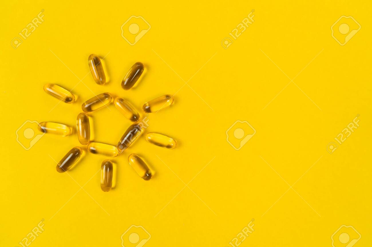 Close up capsules of fish fat oil in the sun shape, omega 3, vitamin e on the yellow background. Healthy food diet. Nutritional supplement - 123761694 Close up capsules of fish fat oil in the sun shape, omega 3, vitamin e on the yellow background. Healthy food diet. Nutritional supplement - 123761694