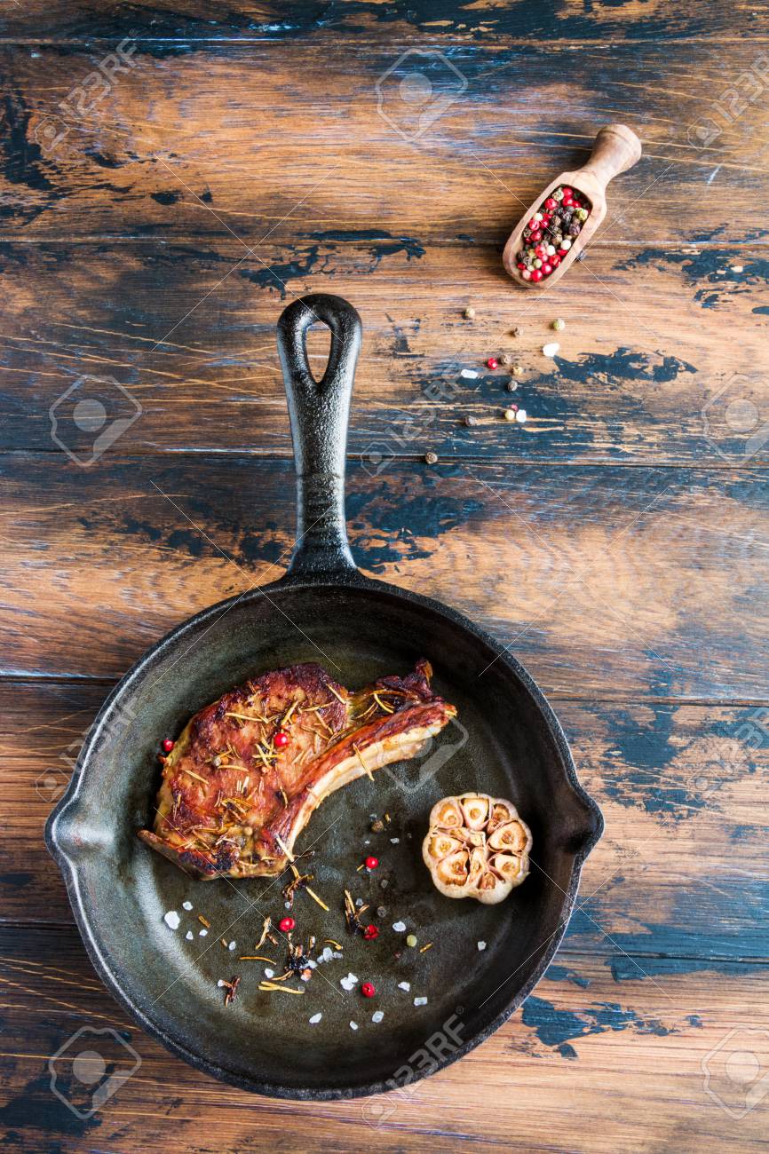 Rib Eye Pork Steak And Baked Garlic In Black Cast Iron Skillet On Wooden Rustic Table Red Pepper Top View Stock Photo Picture And Royalty Free Image Image 70615943