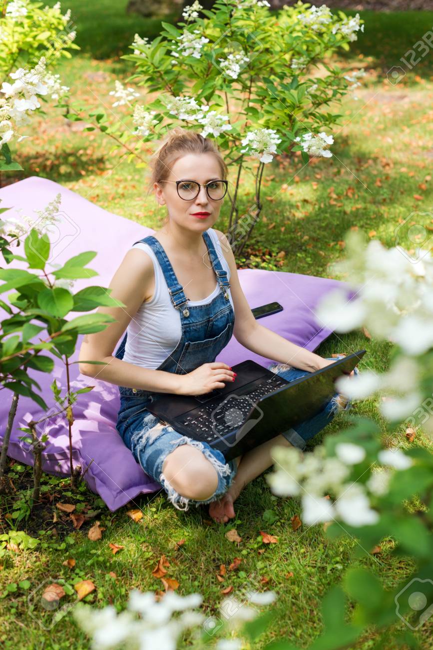 フリーランサーは 庭での作業します 書いて インターネットでネット サーフィンします リラックスできる公園エリアで楽しんで若い女性 遠隔教育 フリーランス コンセプト の写真素材 画像素材 Image