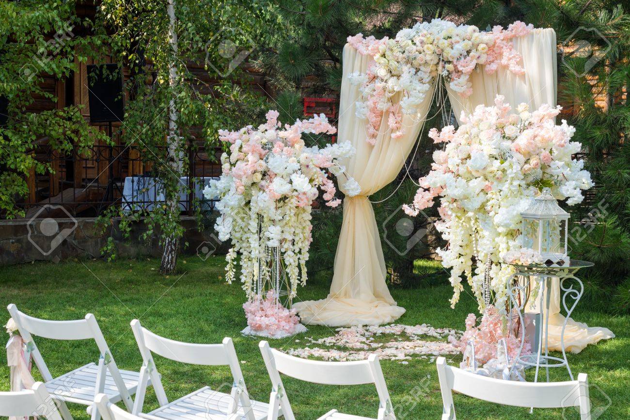 結婚式のアーチは 屋外で布や花で飾られました 美しい結婚式を設定します 庭に緑の芝生の上の結婚式 フラワーアレンジメント お祝い装飾の一部です の写真素材 画像素材 Image
