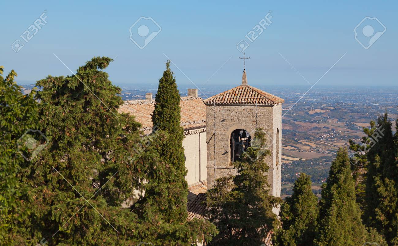 The cross on the roof of a church between the trees against the blue sky. Bell tower. - 89367926 The cross on the roof of a church between the trees against the blue sky. Bell tower. - 89367926