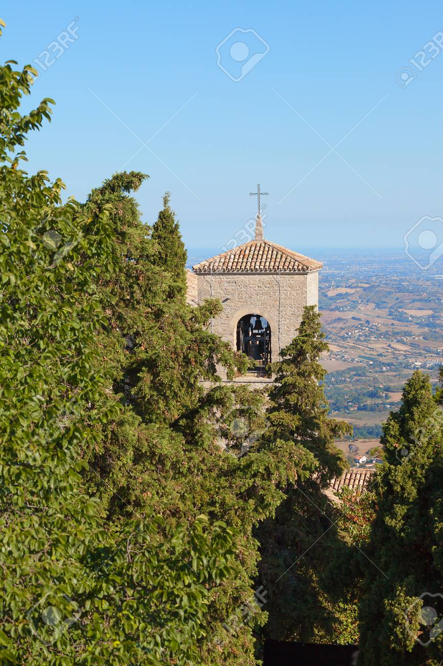 The cross on the roof of a church between the trees against the blue sky. Bell tower. - 91738651 The cross on the roof of a church between the trees against the blue sky. Bell tower. - 91738651