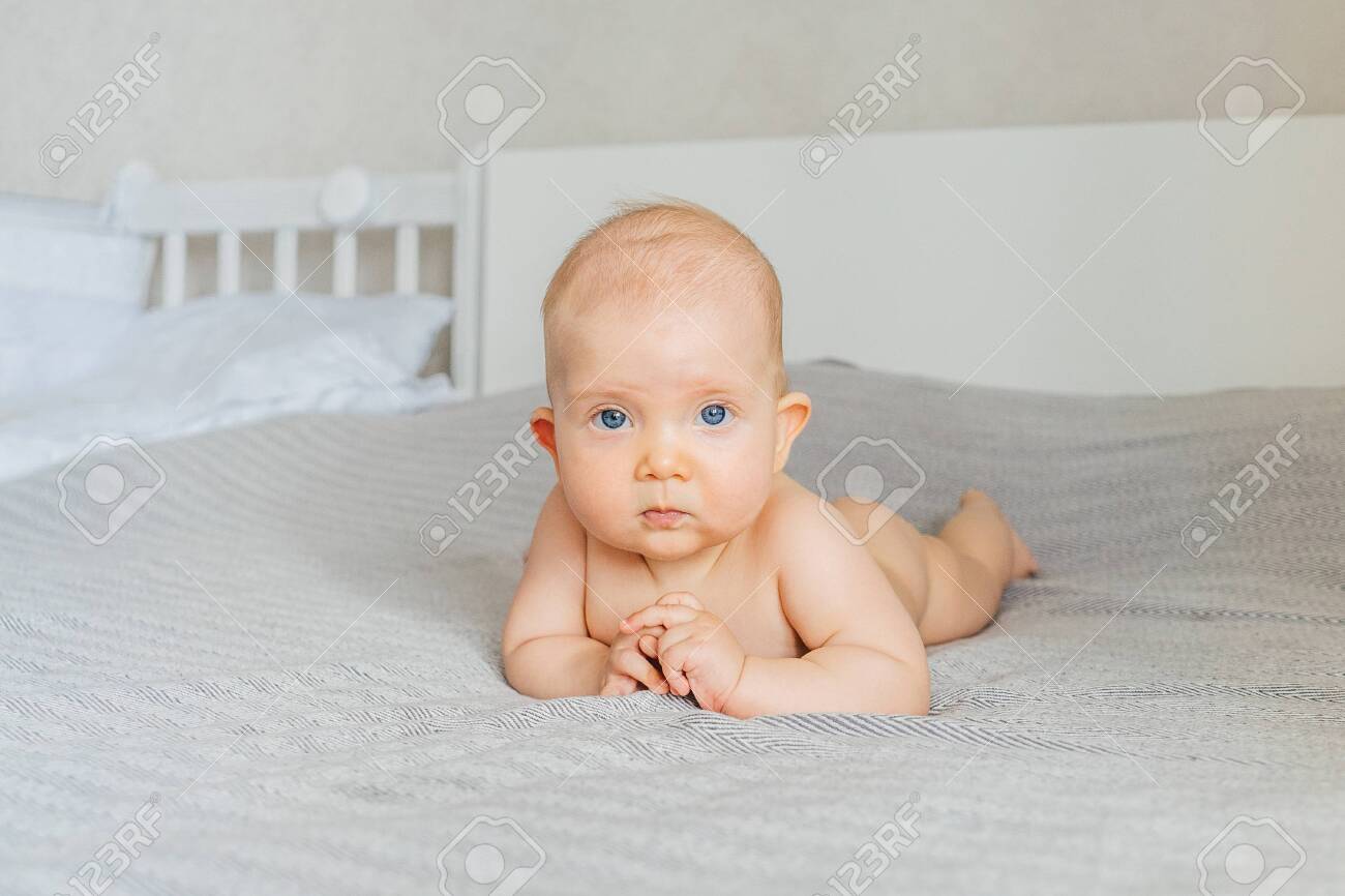 Naked cute baby girl on a light background. At home. - 144710931 Naked cute baby girl on a light background. At home. - 144710931