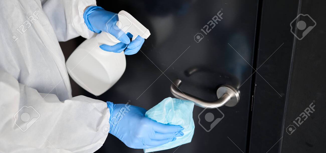 Disinfection, cleaning and washing of door handles. COVID-19. Prevention of coronavirus infection. A woman in a protective suit and blue gloves sprays a disinfectant solution. Prevention of coronavirus infection. - 144854365 Disinfection, cleaning and washing of door handles. COVID-19. Prevention of coronavirus infection. A woman in a protective suit and blue gloves sprays a disinfectant solution. Prevention of coronavirus infection. - 144854365
