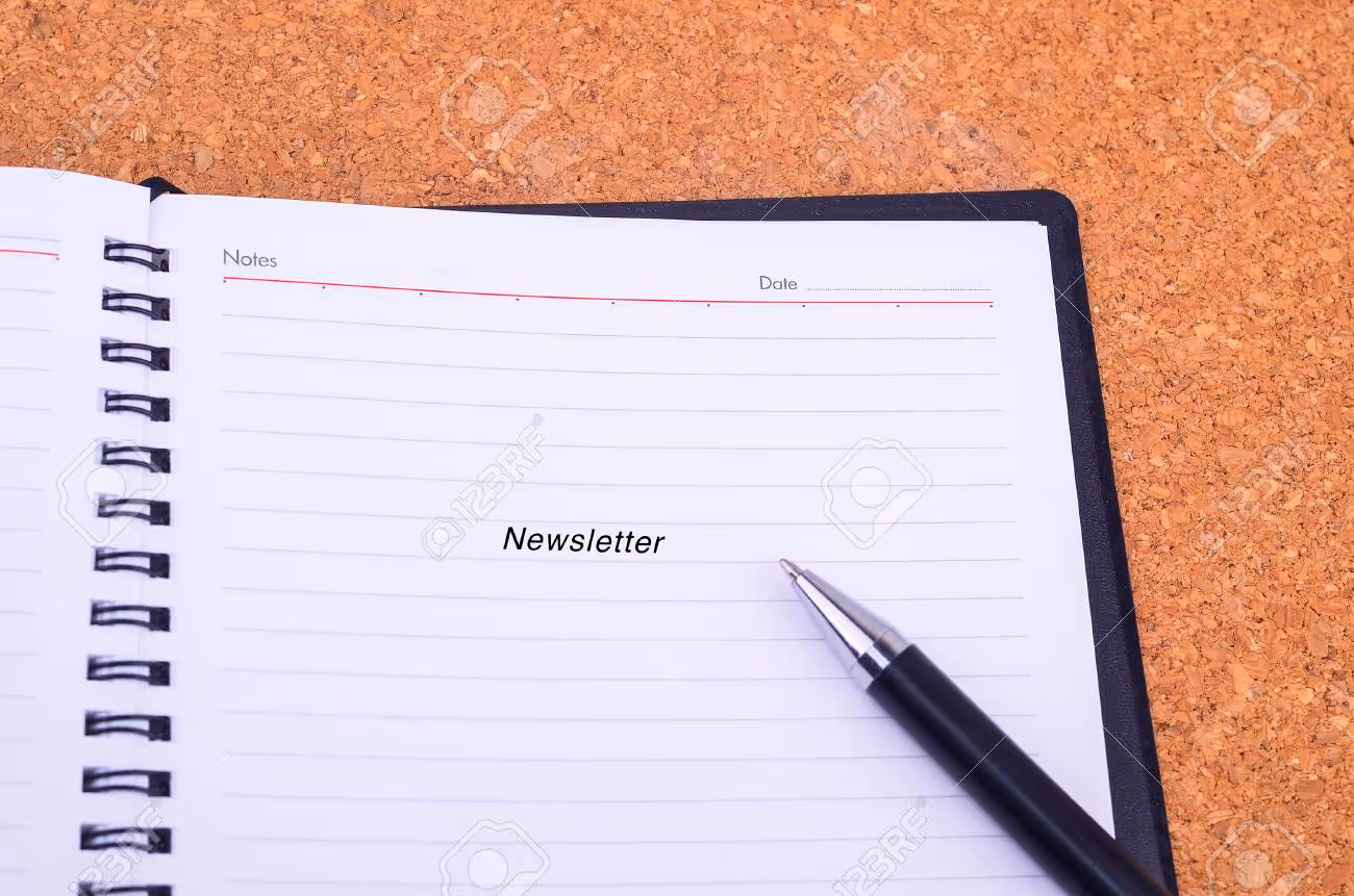 A pen and notebook written Newsletter on a wooden table with copyspace area - 51639106 A pen and notebook written Newsletter on a wooden table with copyspace area - 51639106