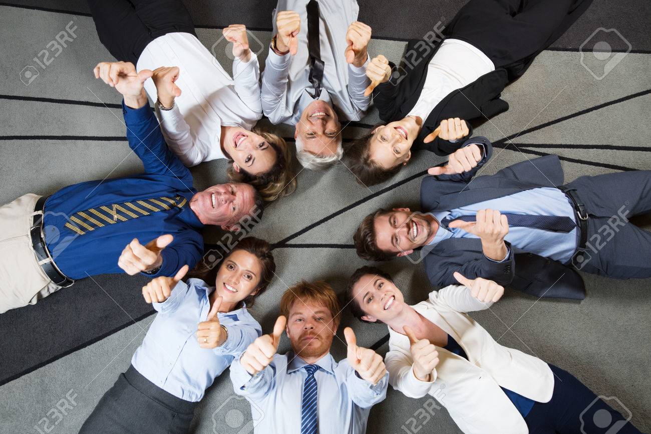 Eight Smiling At Camera Business People Lying On Floor In Circle