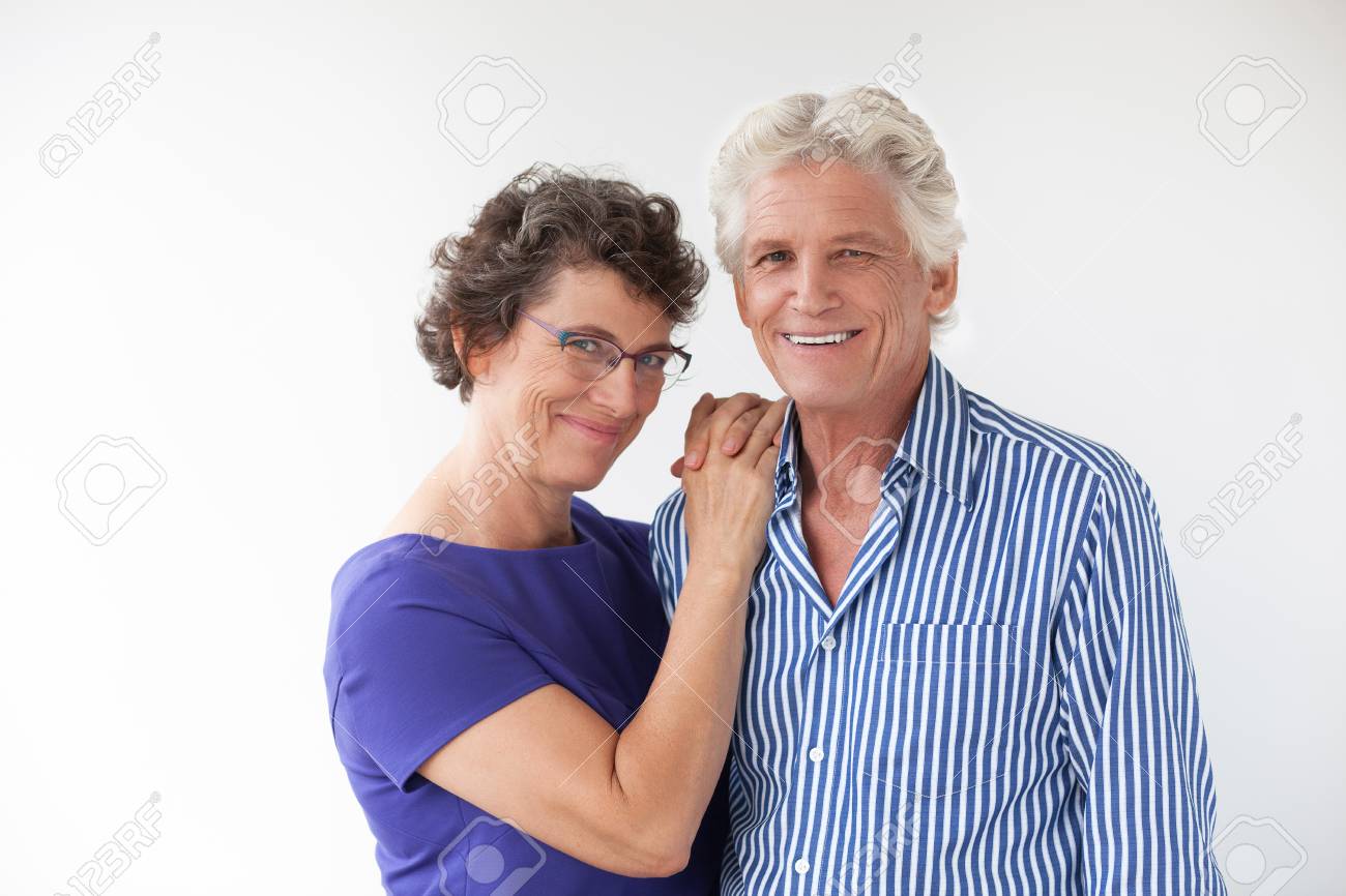 幸せな先輩カップルを抱きしめるとカメラ目線します 夫の肩に手を置く眼鏡笑顔の妻 彼らはお互いをハグします 関係概念 の写真素材 画像素材 Image