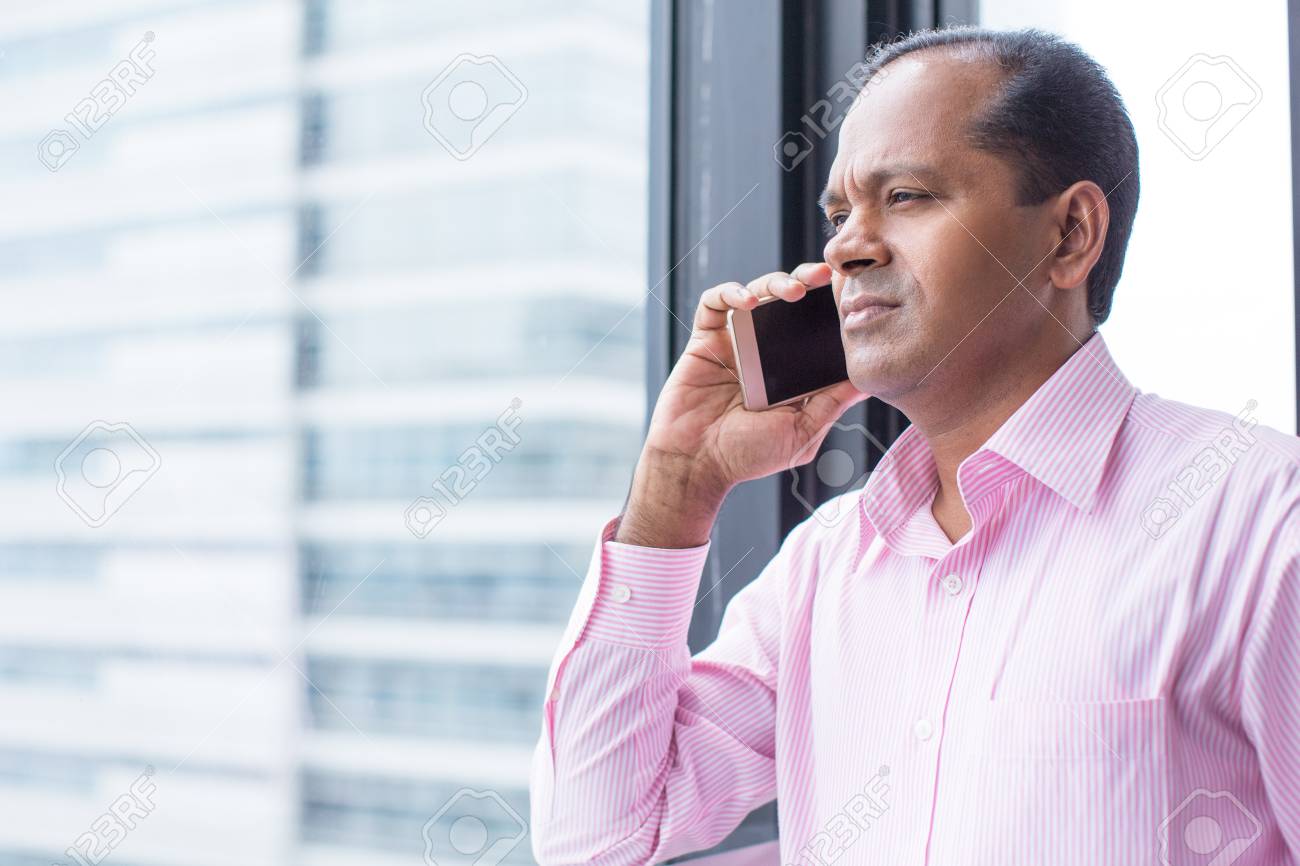 Serious Indian Man Talking On Phone At Window Stock Photo, Picture and  Royalty Free Image. Image 75688170.